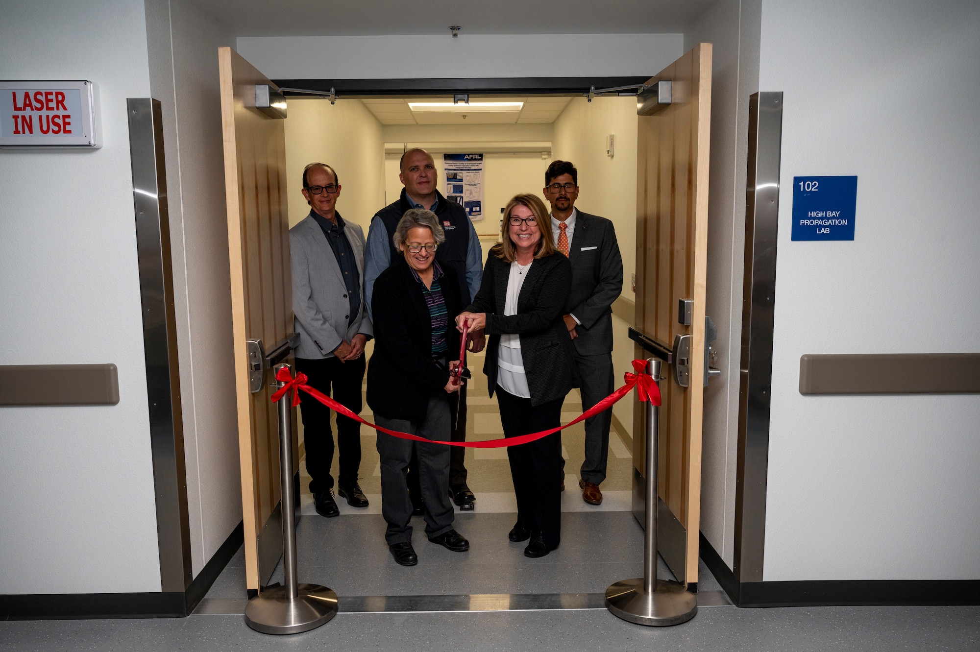 Dr. Shery Welsh, front right, Air Force Laboratory directed energy directorate director, and Dr. Imelda Atencio, front left, AFRL’s directed energy laser division chief, prepare to conduct a ribbon cutting ceremony in celebration of the new Semiconductor Laser Indoor Propagation Range on Kirtland Air Force Base, N.M., Oct. 17, 2023. The range will serve to further aid AFRL in the research and development of propagation studies to fill in critical technology gaps. (U.S. Air Force photo / Airman 1st Class Ruben Garibay)
