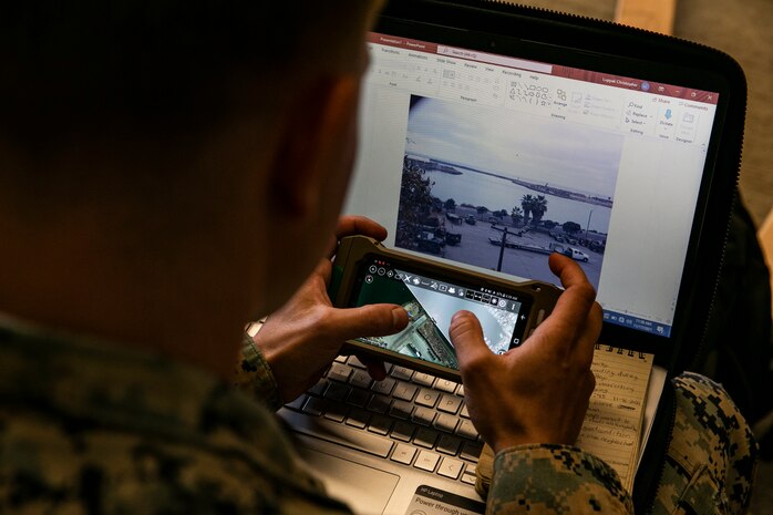 Marine using a phone in front of a laptop computer