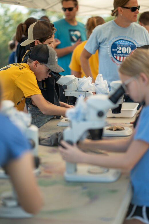 Students looking through microscopes at objects.