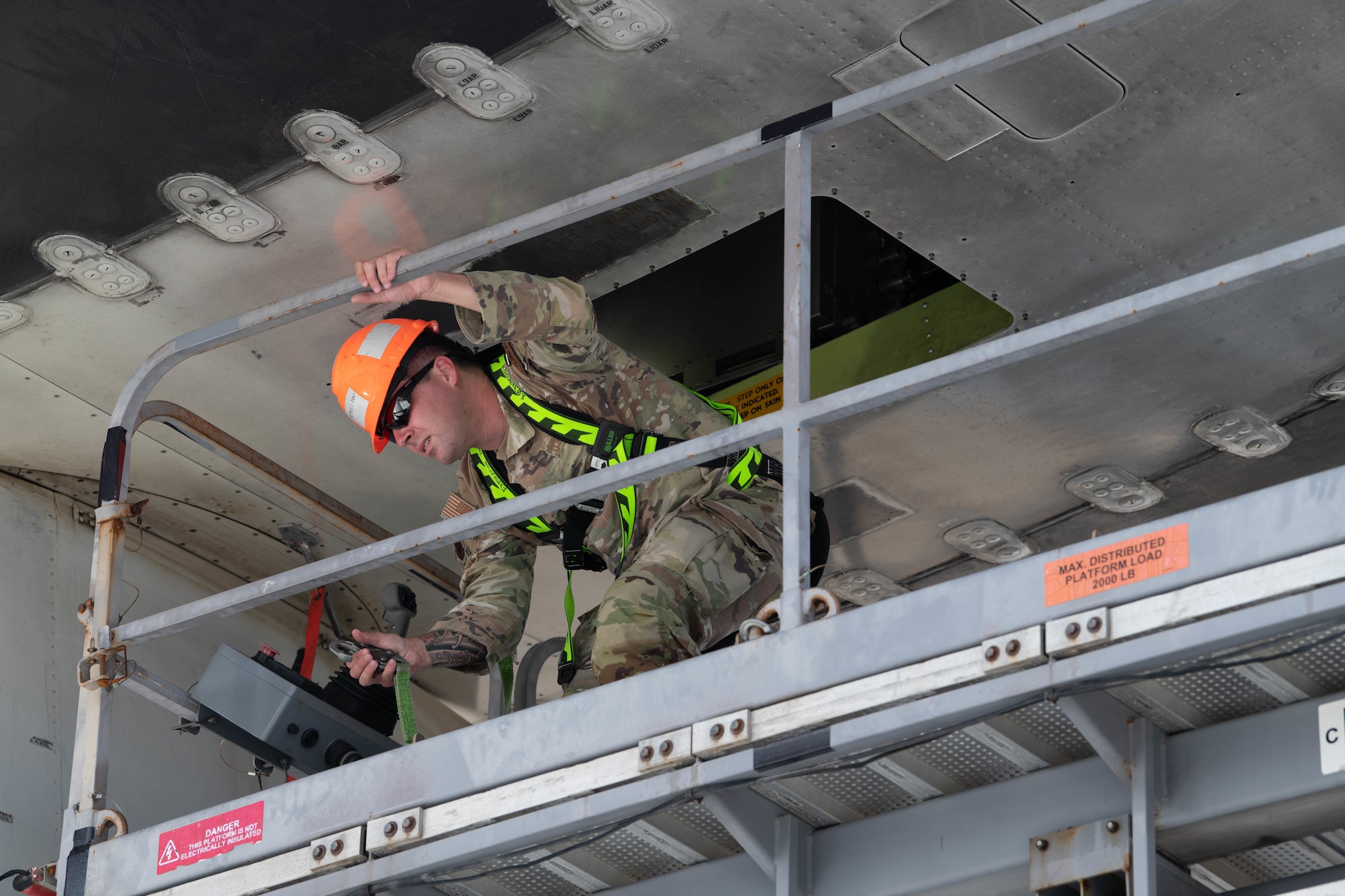 A Airmen secures himself to a skylift during routine maintenace