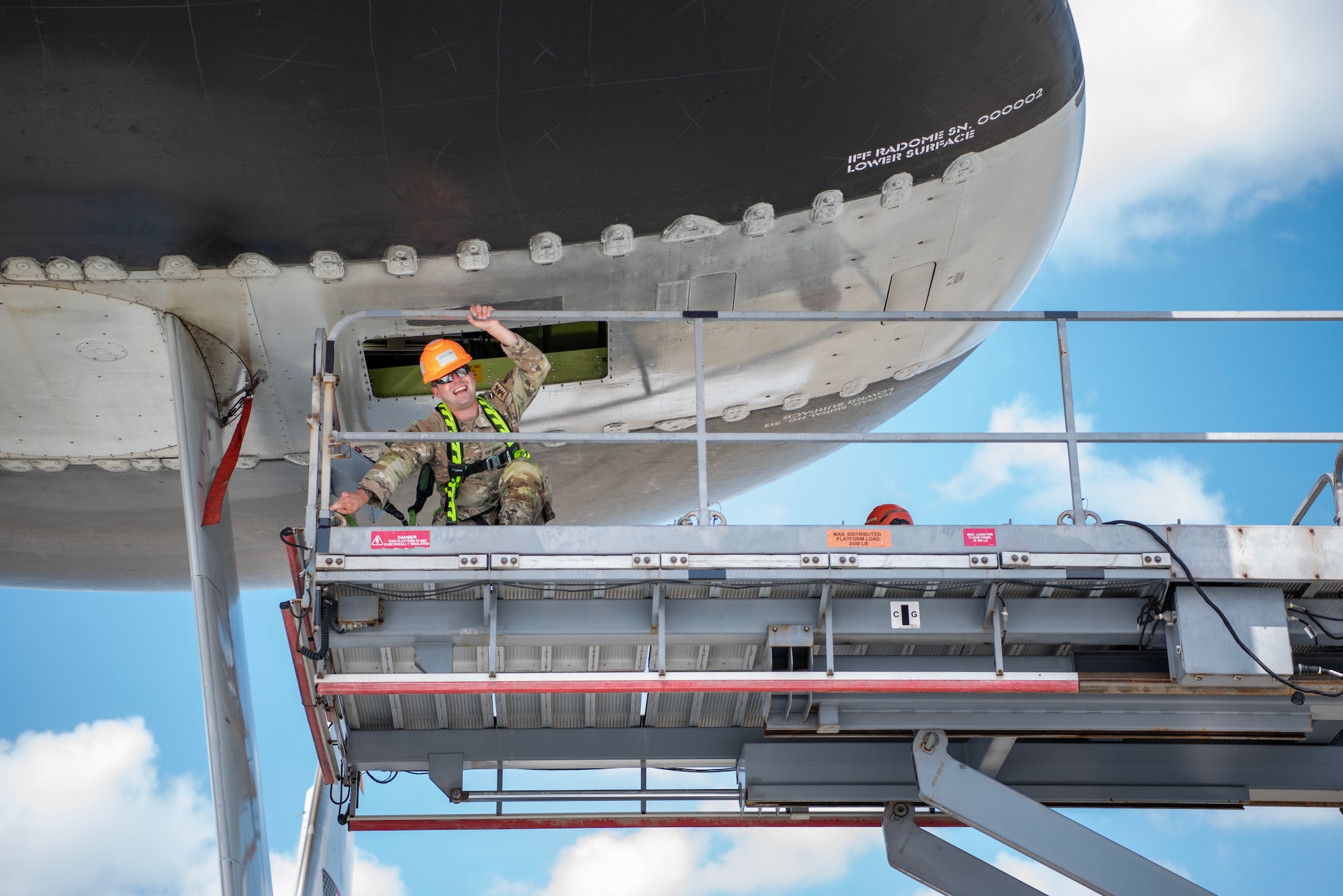 A maintainer exits the hatch of a E-3 Sentry Airborne Warning and Control System aircraft