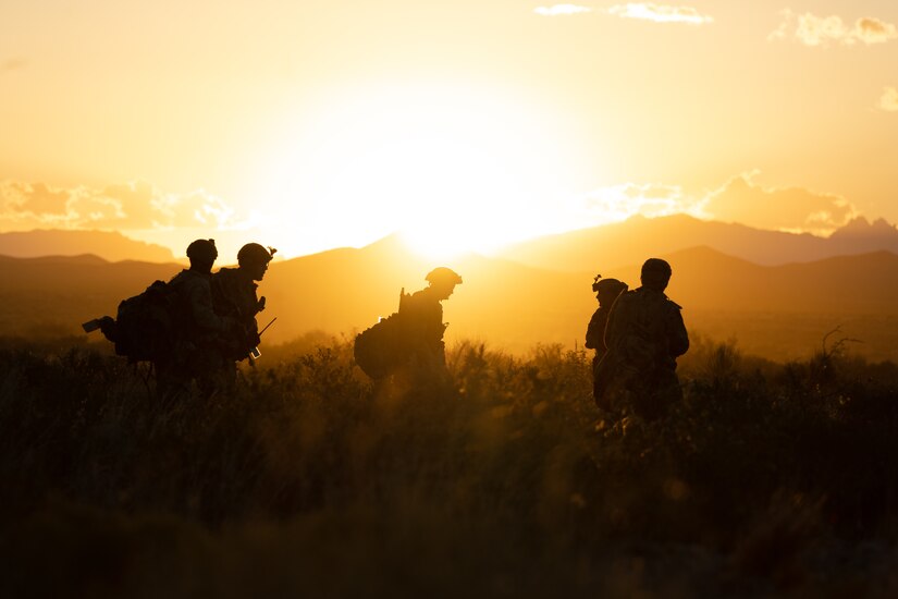 Airmen walk through a field at twilight.