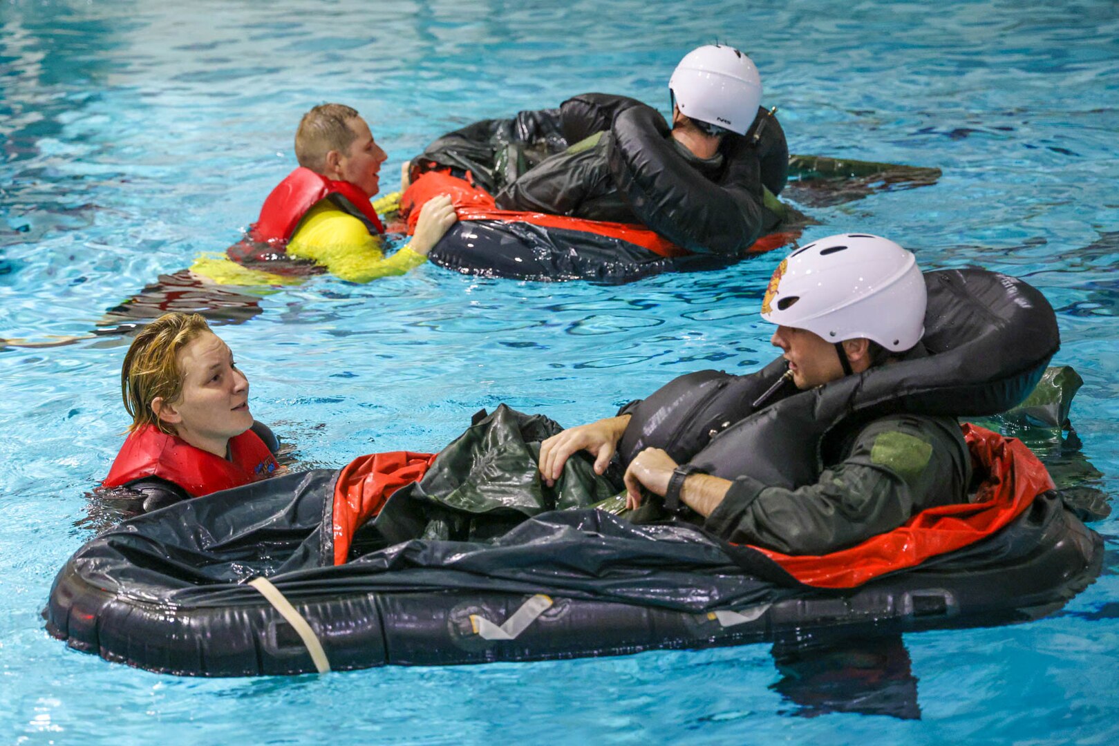 Tech. Sgt. Jasmine Schaffer and Master Sgt. Kenneth Kirchoff, aircrew life support specialists with the 127th Operational Support Squadron, help pilots deploy a life raft during training at Lake Shore High School in Saint Clair Shores, Michigan. Over the October 2023 drill, pilots from the 107th Fighter Squadron, Michigan Air National Guard, practiced water survival tactics during the final phase of their survival, evasion, resistance and escape training refresher course.