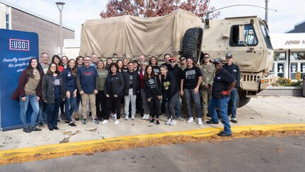 Members of the Illinois National Guard 178th Infantry pose for a photo October 28th with members of the USO and community members at Hershey Highschool in Arlington Heights, Illinois. The group took part in a USO care package event assembling 10,000 care packages for servicemembers.