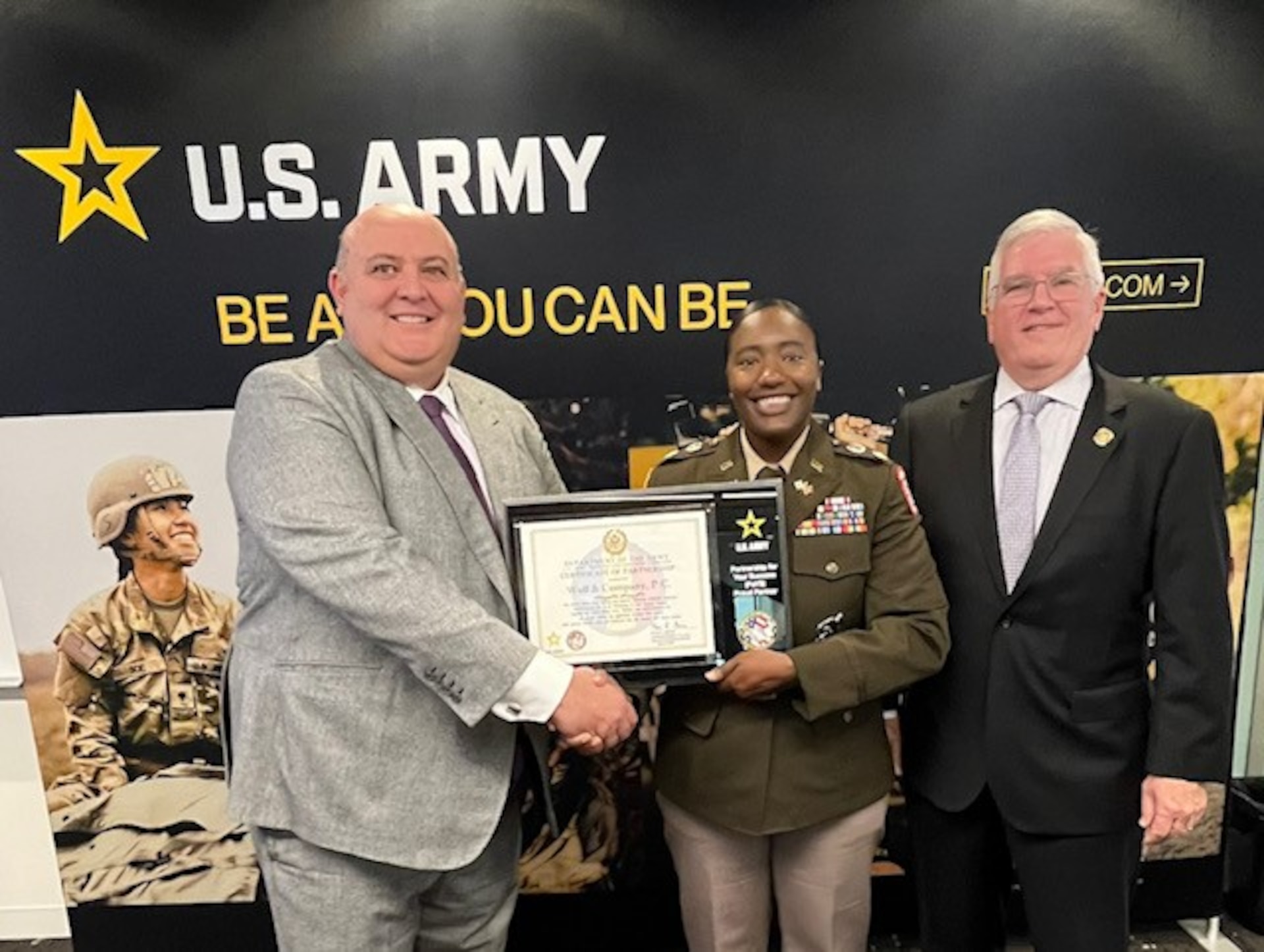 two males posing with a female soldier being presented a certificate.