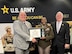 two males posing with a female soldier being presented a certificate.