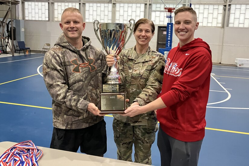 U.S. Air National Guard Col. Lynn Lee, middle, 111th Attack Wing Commander, presents the 111th ATKW Commander's Cup to U.S. ANG Master Sgt. Steven Watson, left, and Master Sgt. Amber Sides, who are both assigned to the 270th Engineering and Installation Squadron here on Oct. 14, 2023. The Commander's Cup, which consisted of tug of war, a sprint medley, pull ups, volleyball, basketball, corn hole and weightlifting, is an event designed to promote camaraderie while highlighting resilience and physical fitness. (U.S. Air National Guard Photo by Staff Sgt. Wilfredo Acosta)