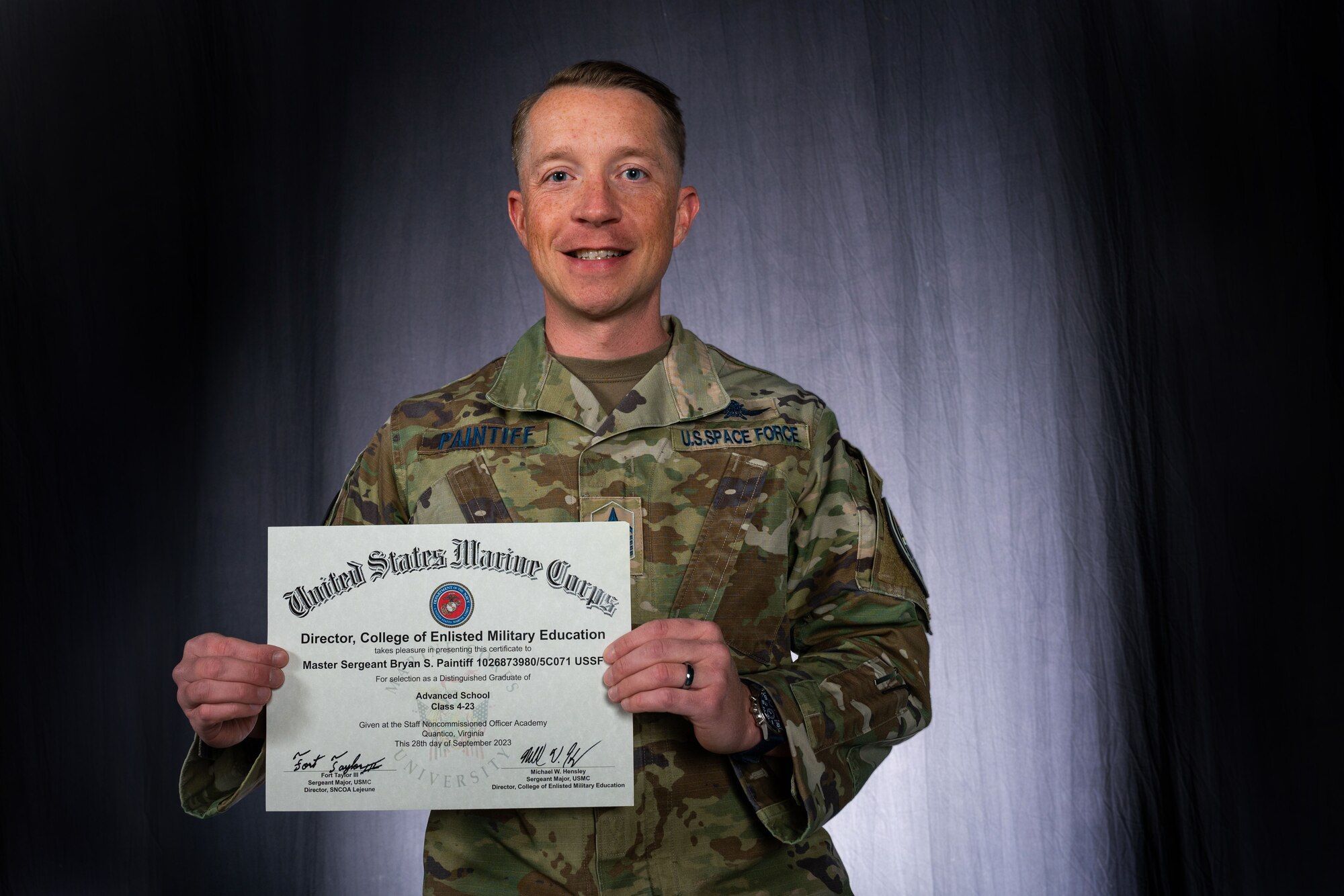 A U.S. Space Force Master Sergeant holds up a certificate for his achievement of winning Distinguished Graduate.