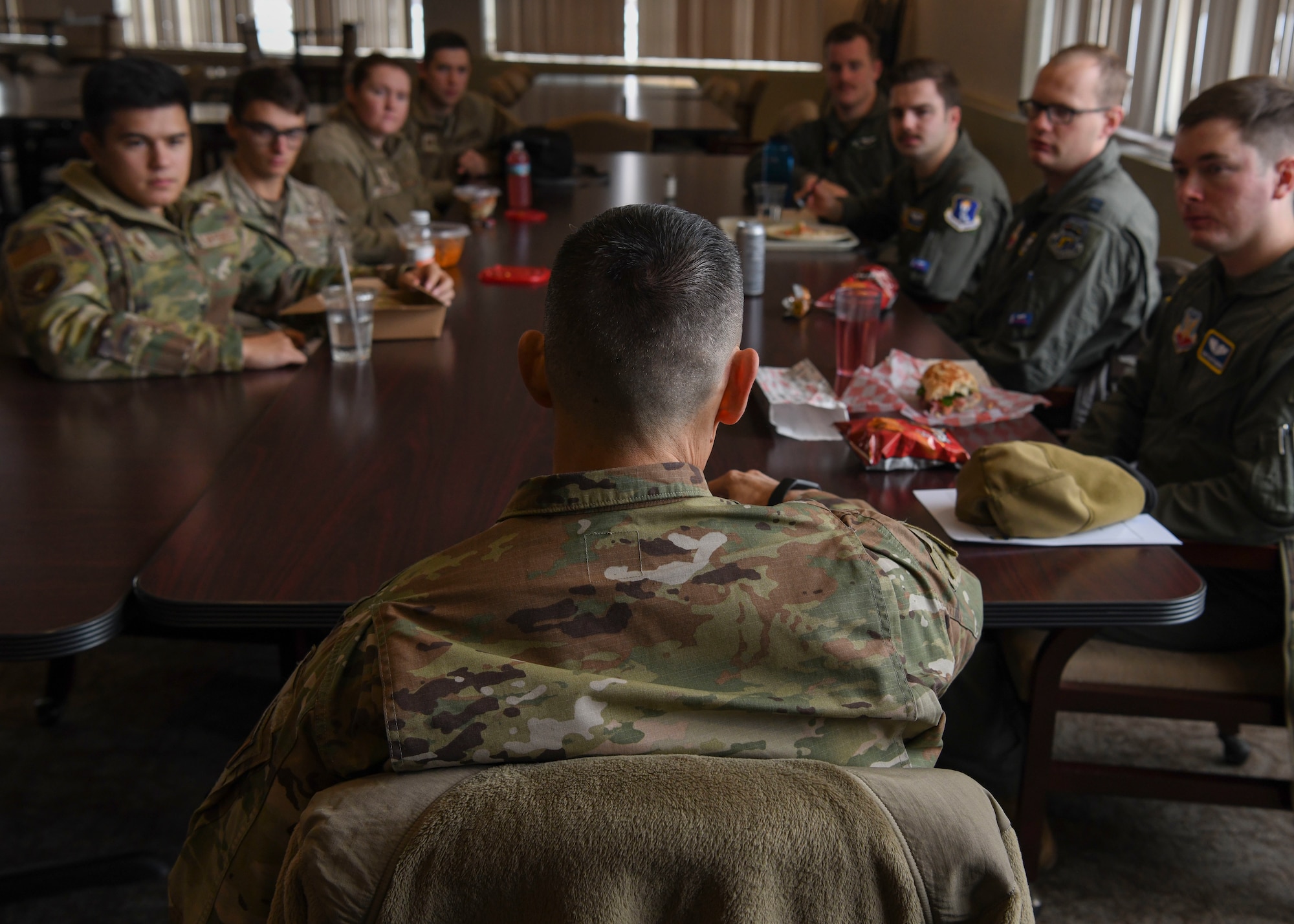 People in green uniforms sit around a table.