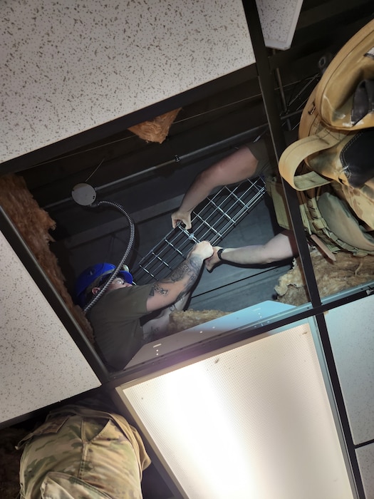 U.S. Air Force Staff Sgt. Jessica Salazar, 85th Engineering Installation Squadron installation technician, installs a cable tray housing fiber optic cable in a facility at Tyndall Air Force Base