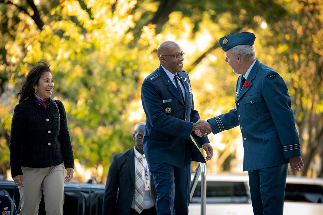 Air Force Gen. CQ Brown, Jr. shakes hands with a Canadian service member outside a building as Brown's wife looks on.