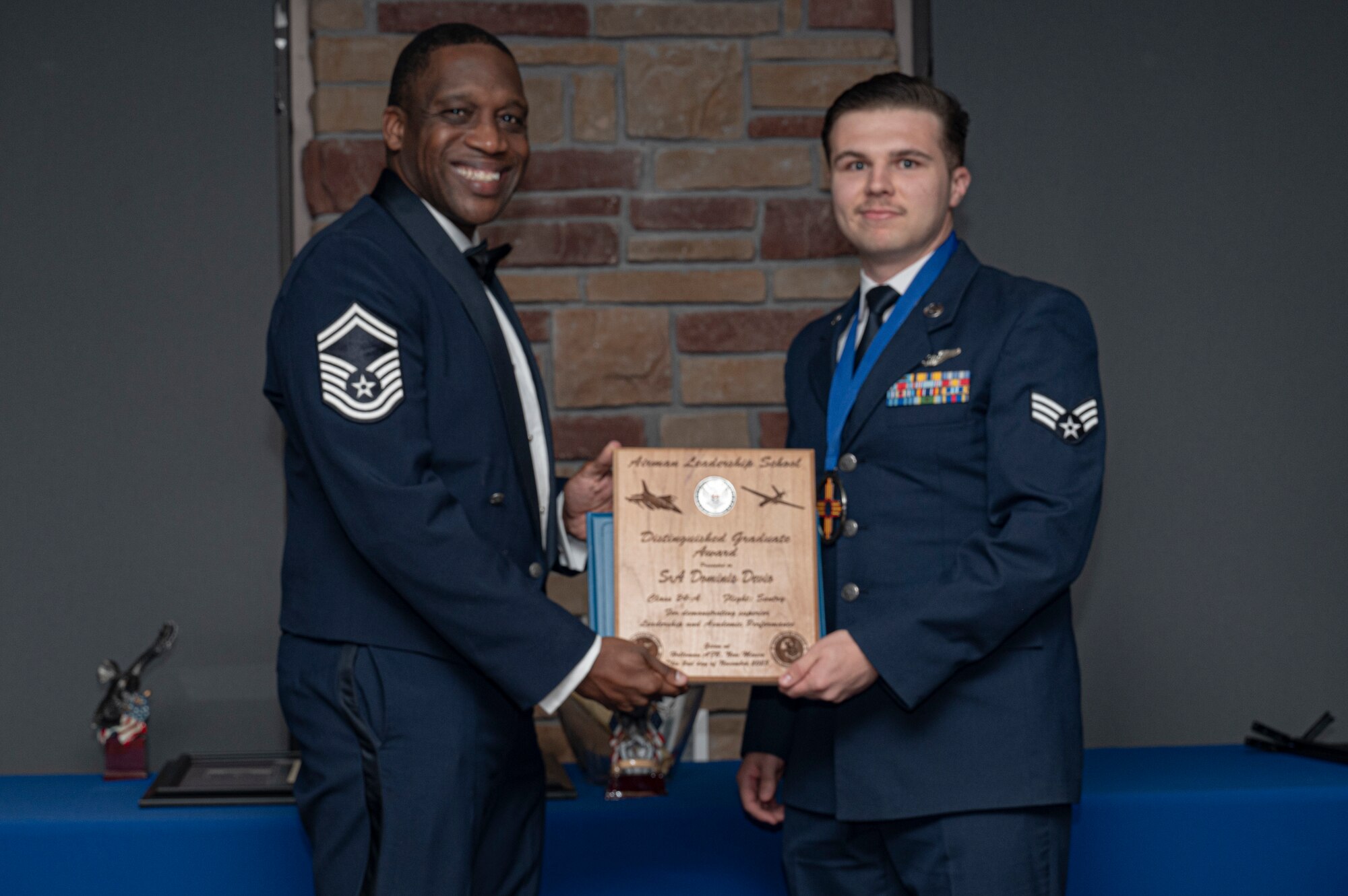 U.S. Air Force Senior Airman Dominic Devio right, Airman Leadership Graduate, accepts the Distinguished Graduate Award from Holloman Top III representative Senior Master Sgt. Rodney Dunn during the graduation of Joel C. Mayo ALS Class 24-A at Holloman Air Force Base, New Mexico, Nov. 2, 2023. The distinguished graduate award is presented to the top 10% of graduates for their performance in academic evaluations and demonstration of leadership. (U.S. Air Force photo by Airman 1st Class Michelle Ferrari)