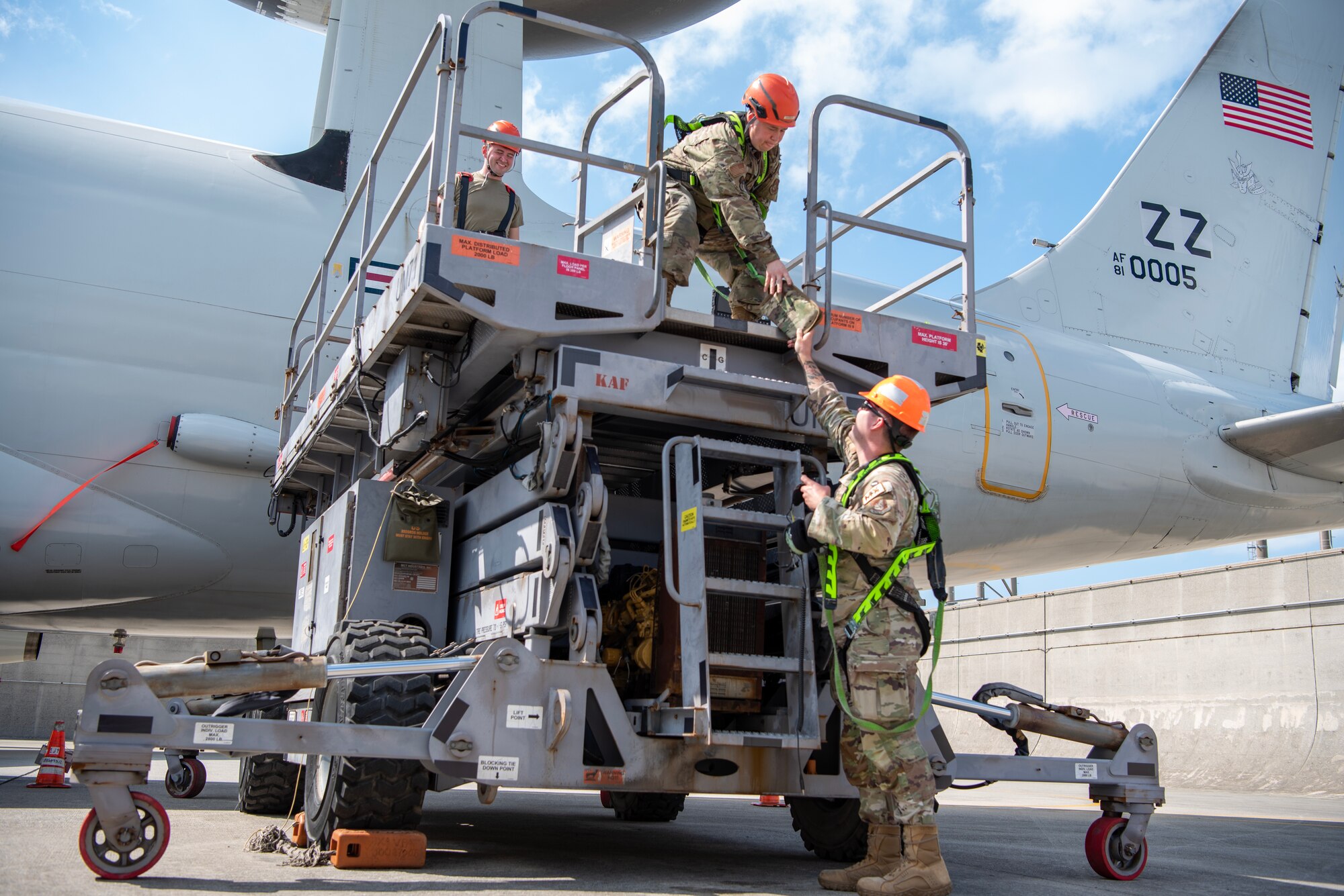 A maintainer hands ear pro to a fellow airmen before starting maintenance