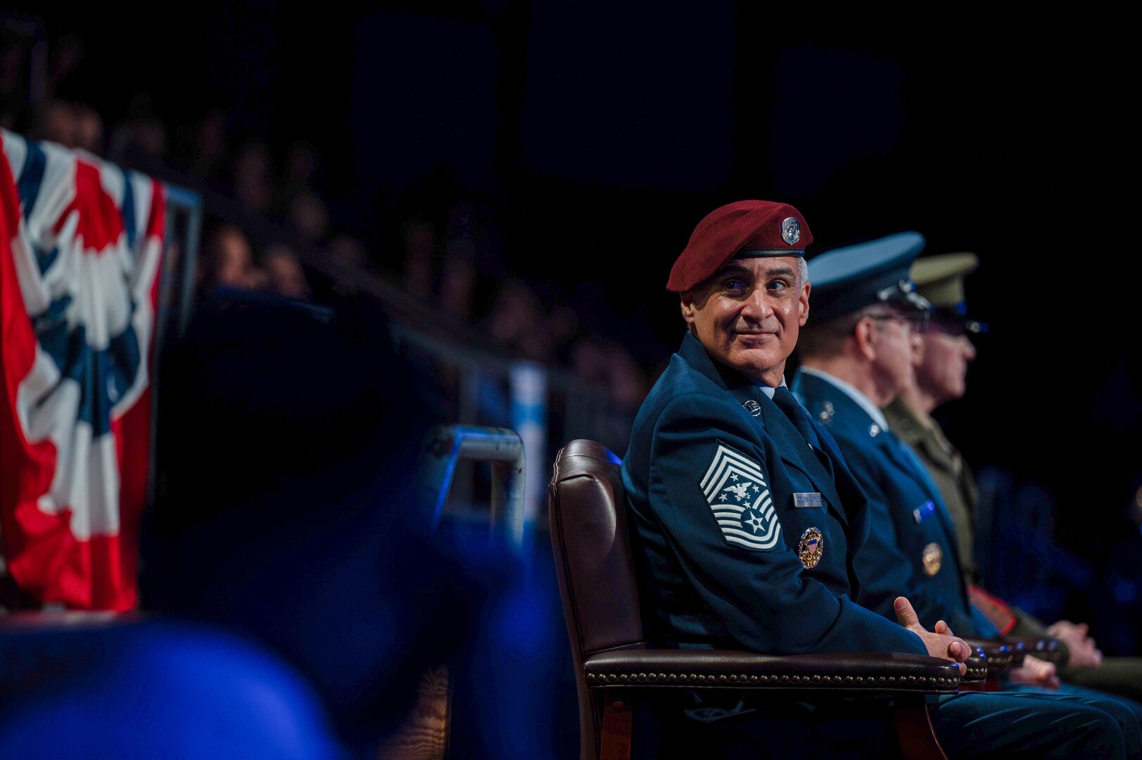 A seated uniformed service member smiles.