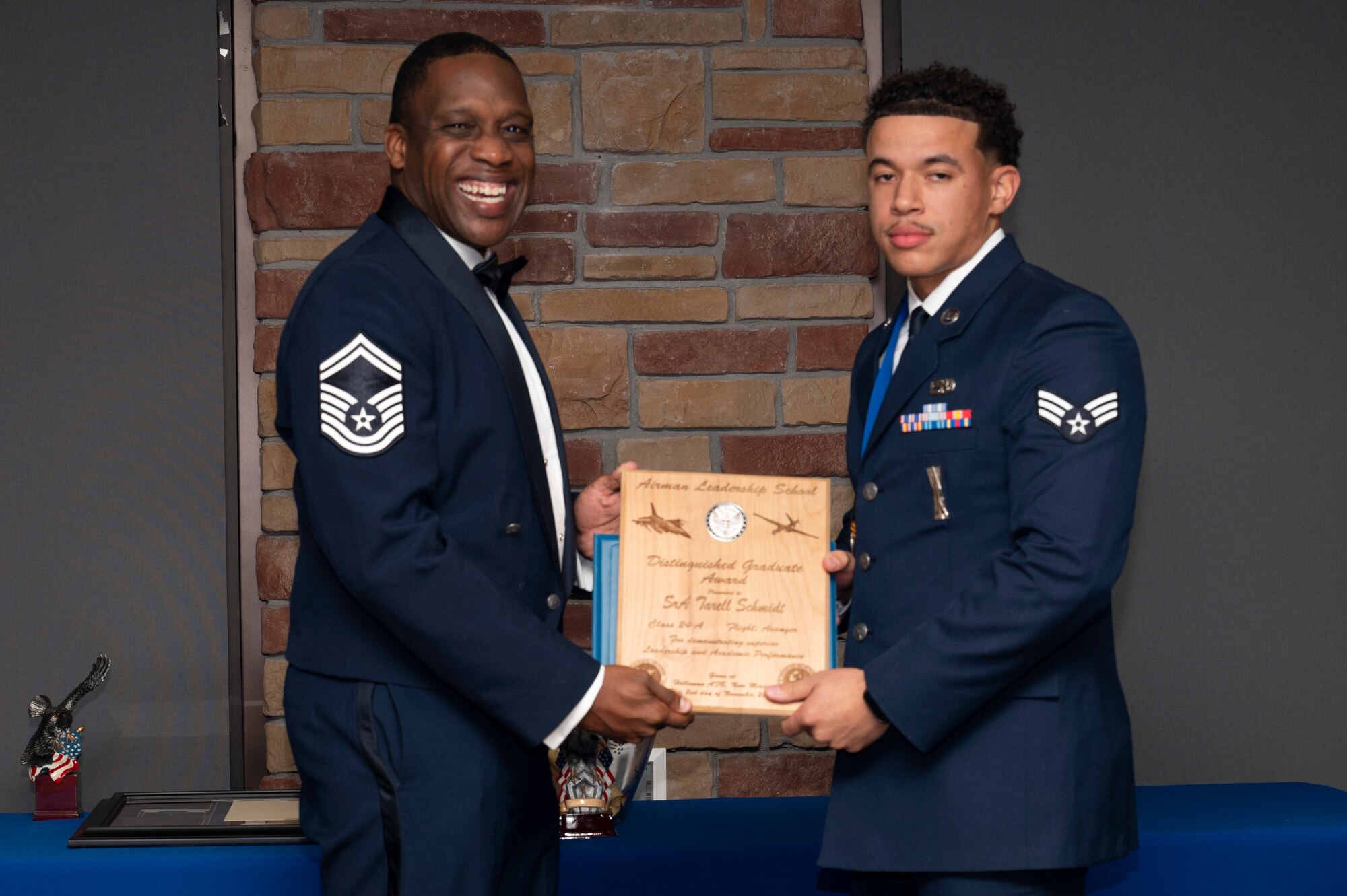U.S. Air Force Senior Airman Tarell Schmidt right, Airman Leadership Graduate, accepts the Distinguished Graduate Award from Holloman Top III representative Senior Master Sgt. Rodney Dunn during the graduation of Joel C. Mayo ALS Class 24-A at Holloman Air Force Base, New Mexico, Nov. 2, 2023. The distinguished graduate award is presented to the top 10% of graduates for their performance in academic evaluations and demonstration of leadership. (U.S. Air Force photo by Airman 1st Class Michelle Ferrari)