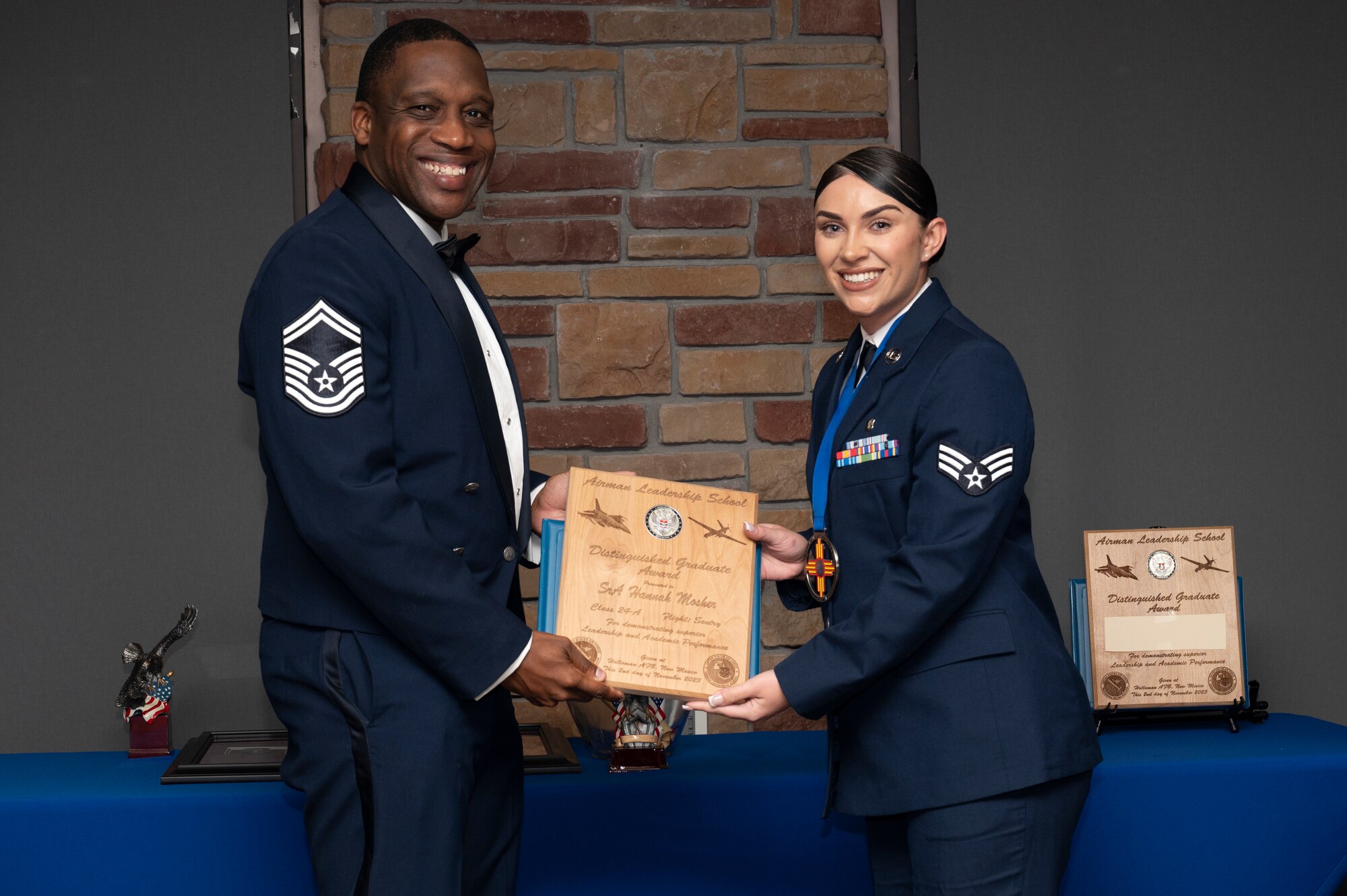 U.S. Air Force Senior Airman Hannah Mosher, right, Airman Leadership Graduate, accepts the Distinguished Graduate Award from Holloman Top III representative Senior Master Sgt. Rodney Dunn during the graduation of Joel C. Mayo ALS Class 24-A at Holloman Air Force Base, New Mexico, Nov. 2, 2023. The distinguished graduate award is presented to the top 10% of graduates for their performance in academic evaluations and demonstration of leadership. (U.S. Air Force photo by Airman 1st Class Michelle Ferrari)