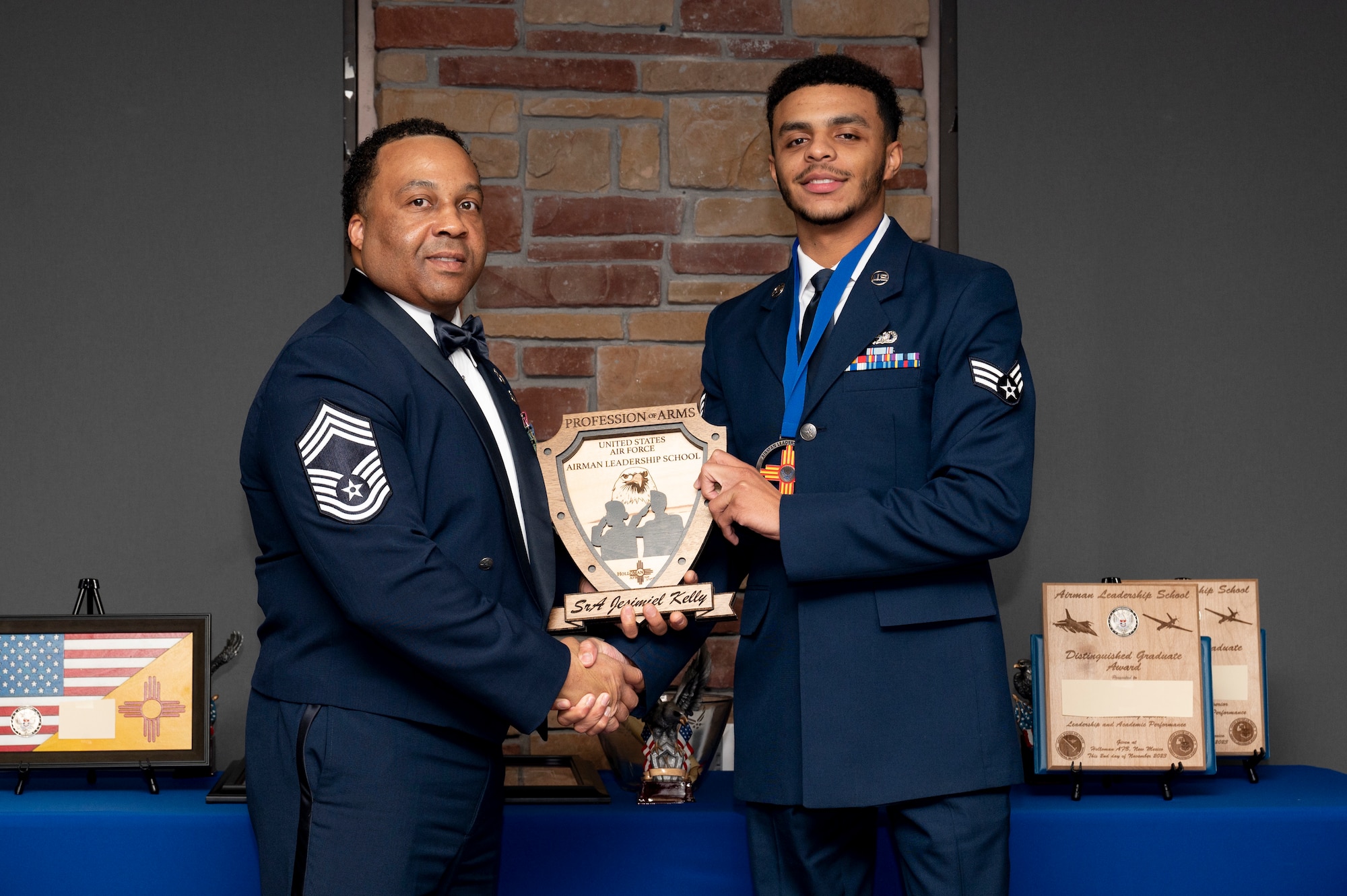 U.S. Air Force Senior Airman Jesimiel Kelly, right, accepts the Profession of Arms Award from Chief Master Sgt. Tyrell McClora, during the graduation of Joel C. Mayo ALS Class 24-A at Holloman Air Force Base, New Mexico, Nov. 2, 2023. The profession of arms award recognizes the student who most embodies the profession of arms, which is demonstrated with a comprehensive understanding of the warrior ethos, oath of enlistment, and the airman’s creed. (U.S. Air Force photo by Airman 1st Class Michelle Ferrari)