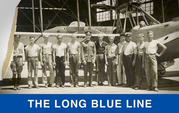 A July 1921 photo of staff at Air Station Morehead City, the Coast Guard’s first air station and crew, in front of a flying boat and hangar. Officer standing in the center is Capt. William Wishar with another officer and enlisted men posing in the hot summer sun. (U.S. Coast Guard photo)