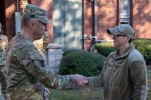U.S. Air Force Maj. Gen. John Klein, U.S. Air Force Expeditionary Center commander, left, coins Tech. Sgt. Christina Ferguson, 628th Operational Medical Readiness Squadron public health non-commissioned officer in charge, during a visit to Joint Base Charleston, South Carolina, Nov. 2, 2023.