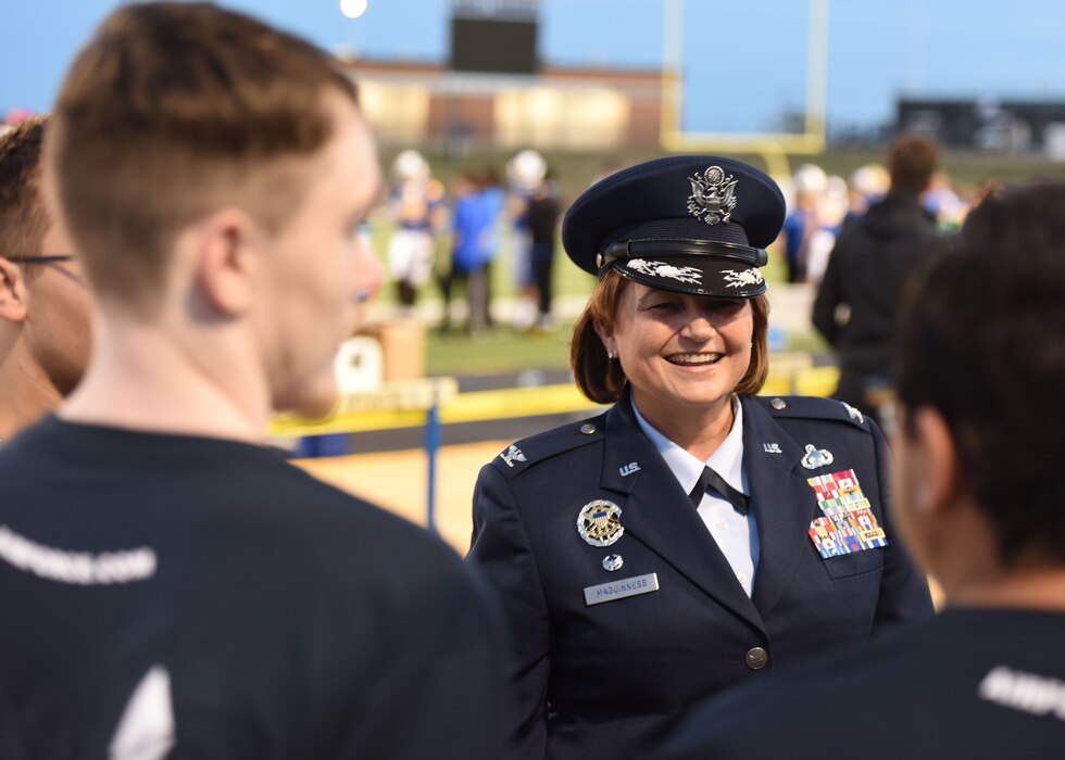 U.S. Air Force Col. Angelina Maguinness, 17th Training Wing commander, talks with new Air Force enlistees before swearing them in at Military Appreciation Day, San Angelo, Texas, Nov. 4, 2023. The enlistees officially started their military journey during the football game’s halftime show. (U.S. Air Force photo by Staff Sgt. Nathan Call)