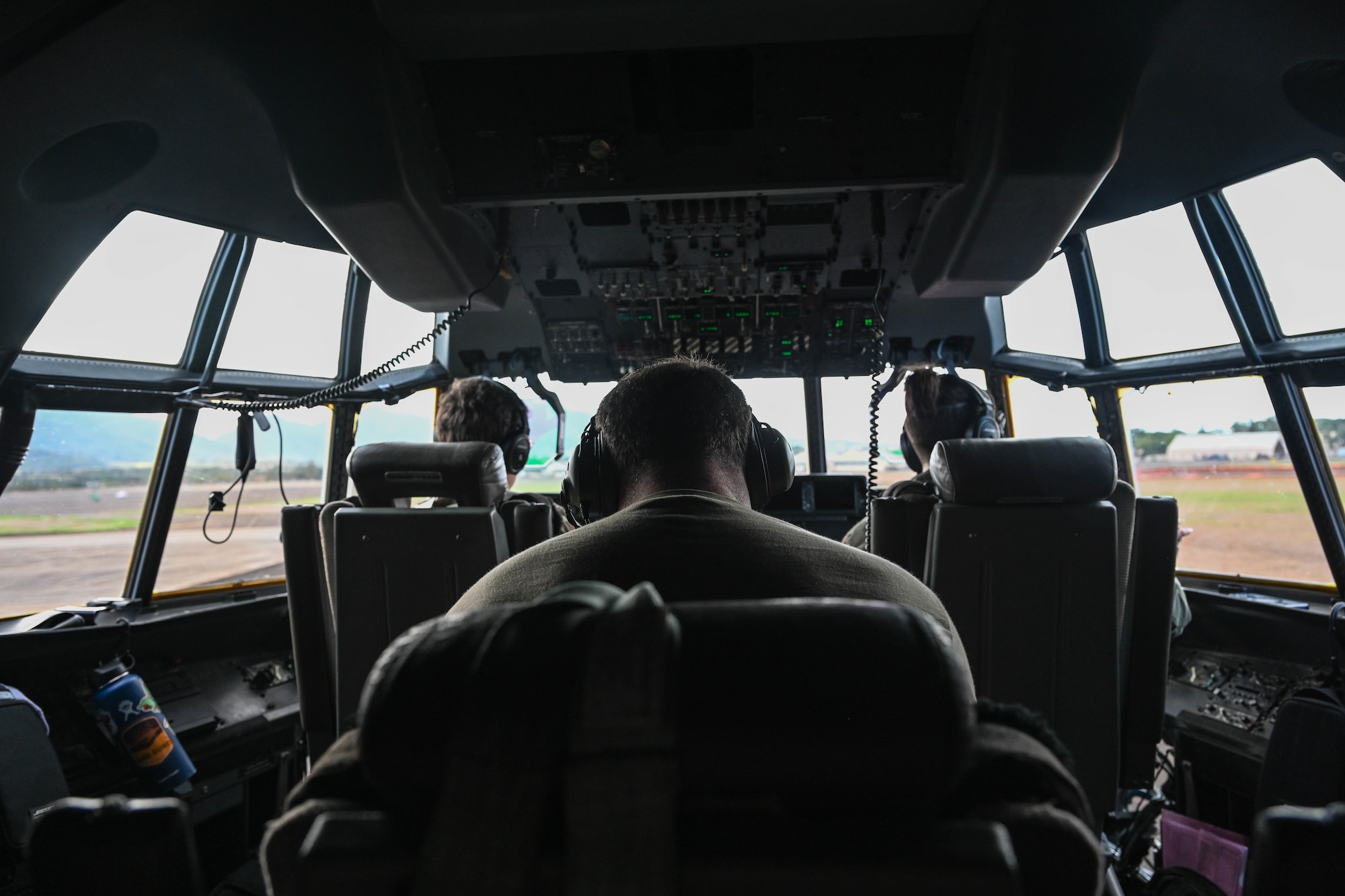 Airmen sit in the cockpit of an aircraft.