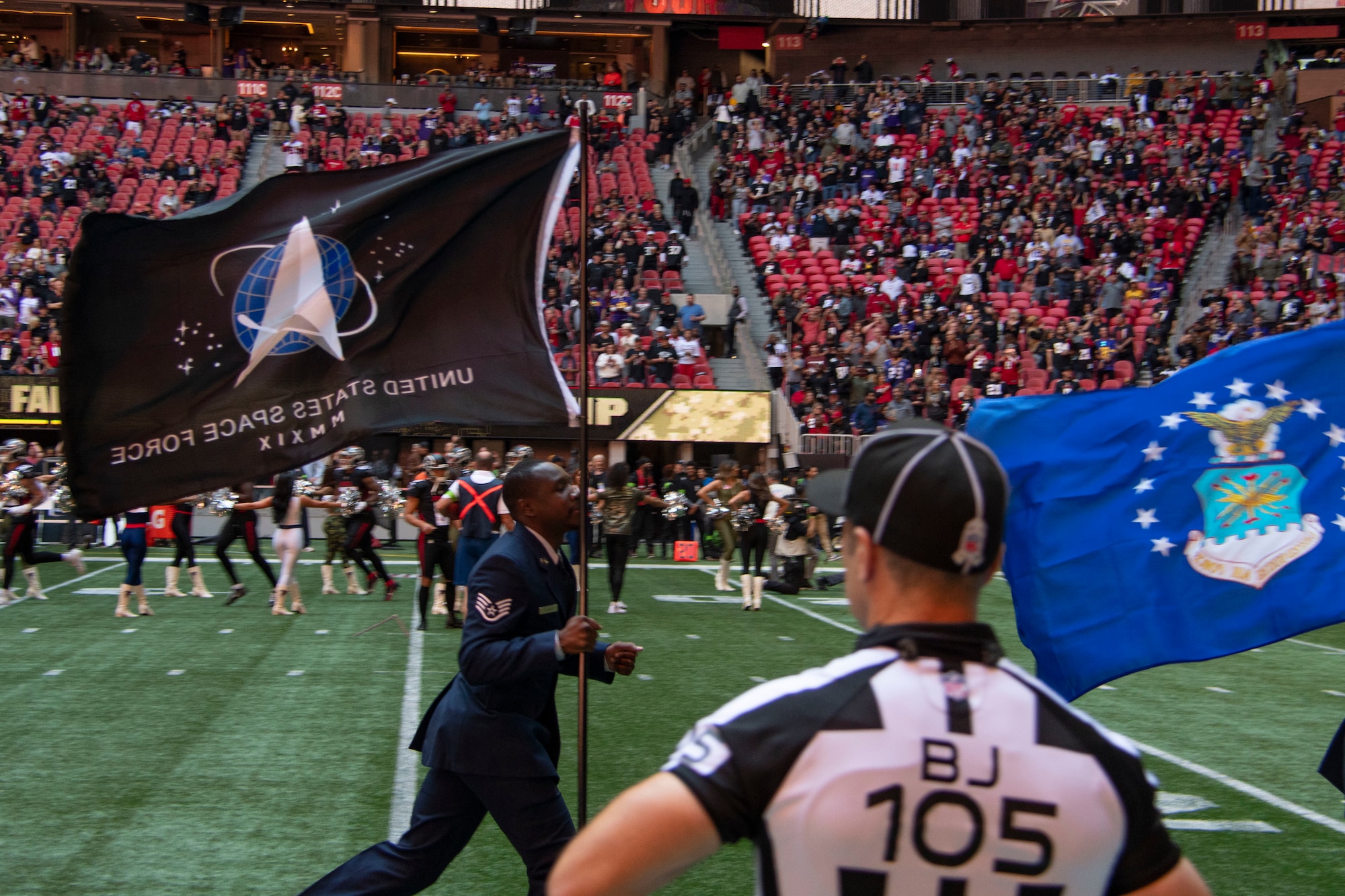 Man runs with flag on football field.