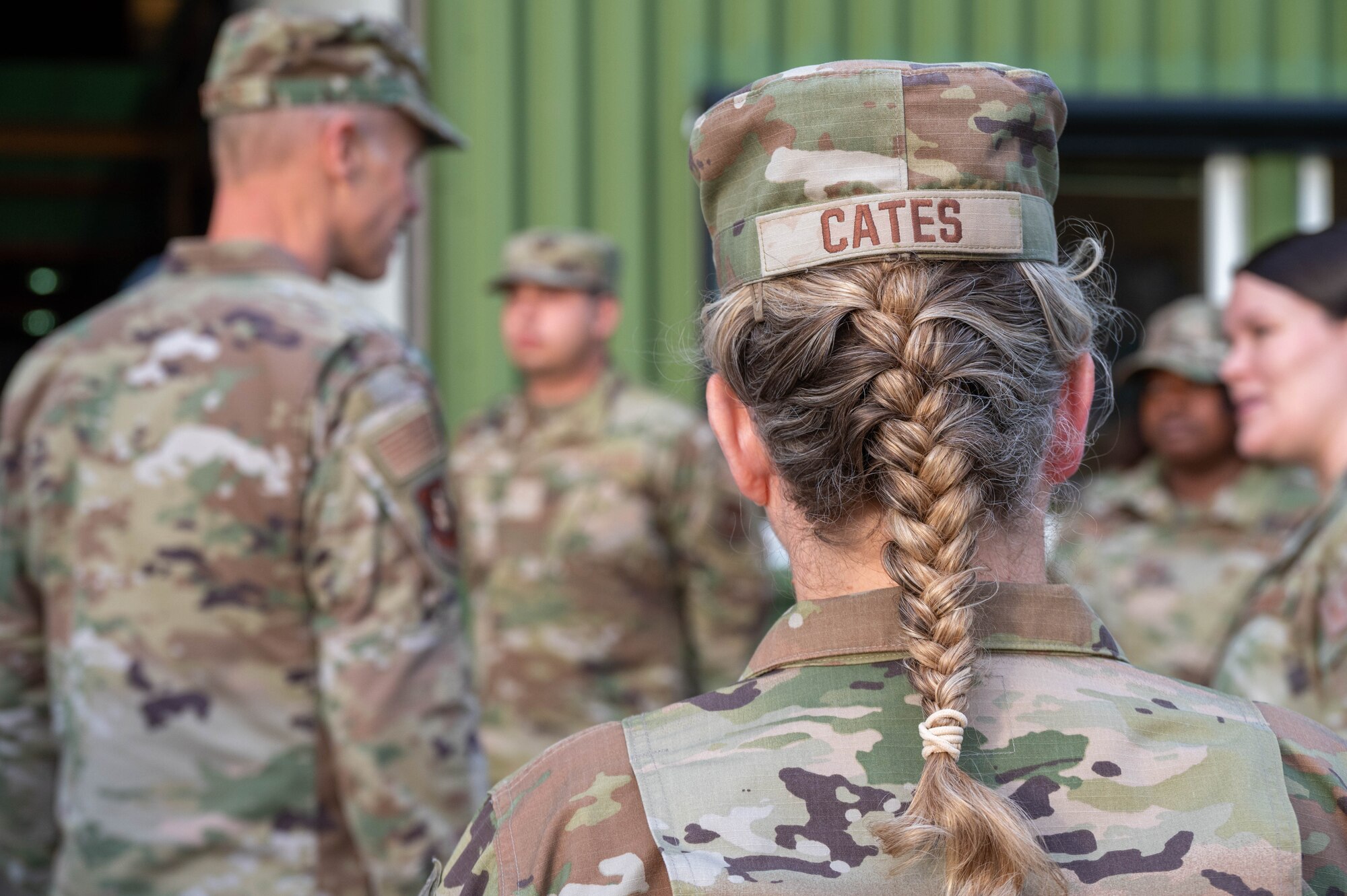 The back of CMSgt Cates head, displaying her hat's nametape and braided hair.