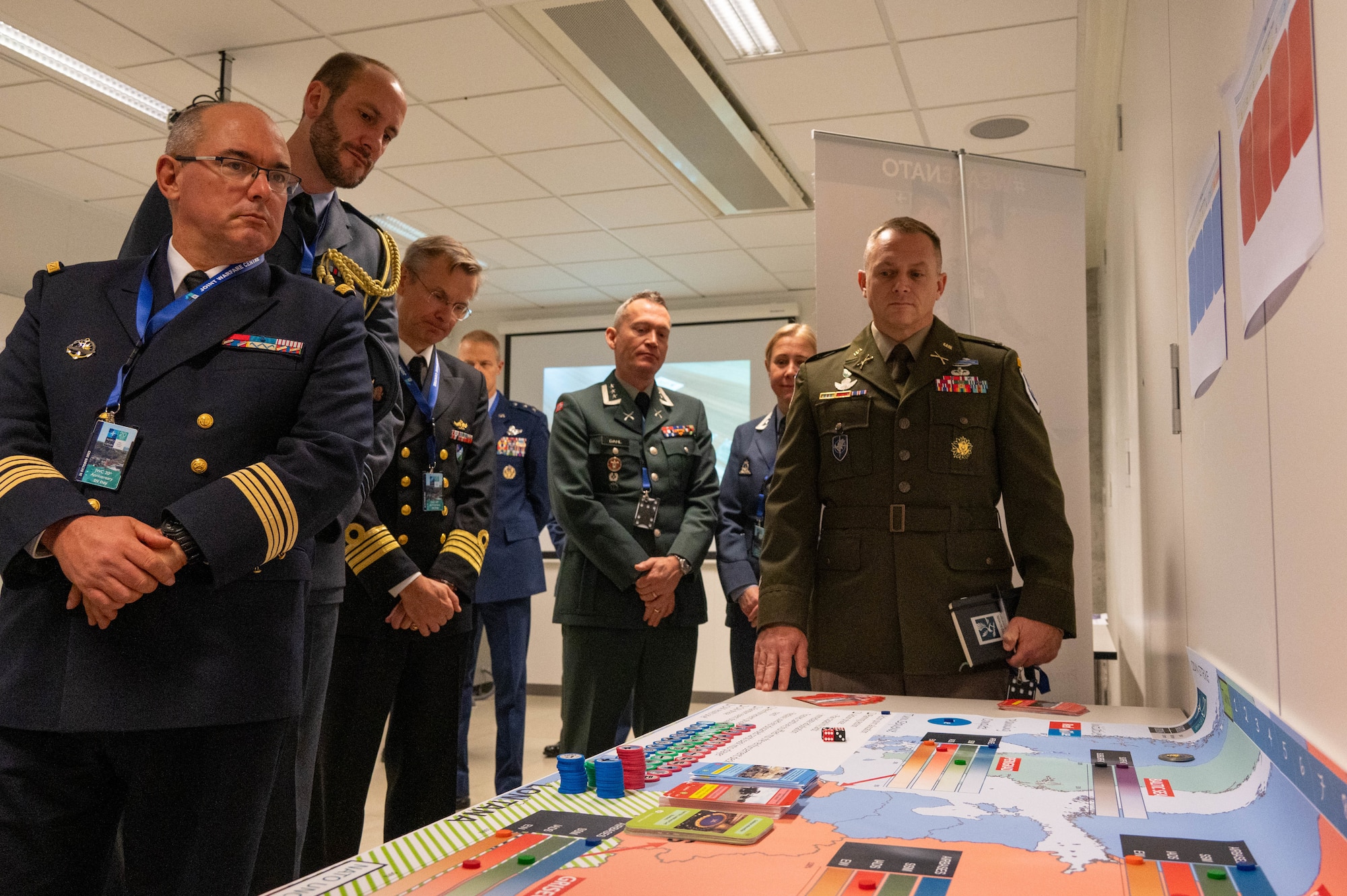 Military dignitaries view a wargaming board.