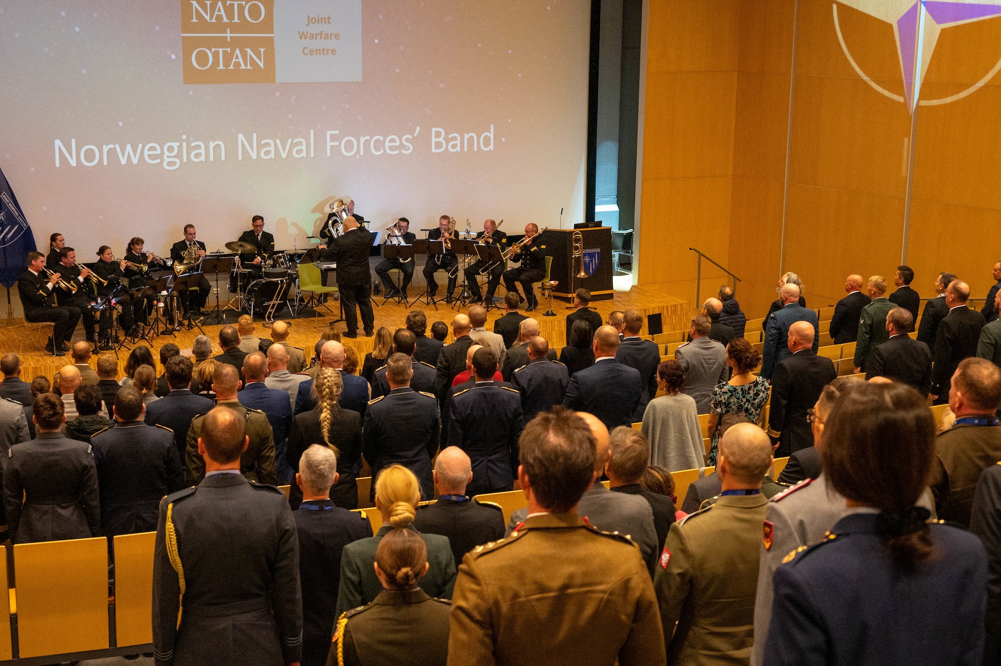 Military and civilian dignitaries stand for the official NATO hymn.