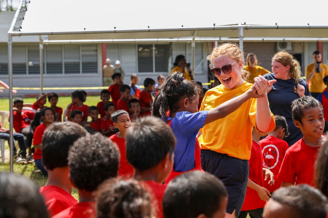 A sailor dances with children.