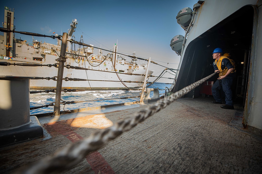 A seaman heaves  a line during a replenishment.