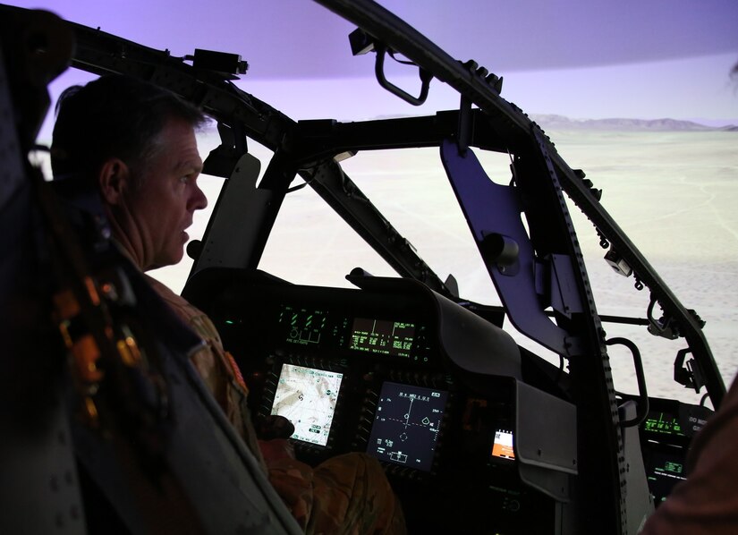 A service member sits in the cockpit of an aviation simulator.
