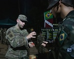 New York National Guard Sgt. 1st Class Brian Pasquale, combat medic assigned to the 466th Medical Company Area Support, discusses creating a modified shotgun shell with a Brazilian Army jungle trainer at the night portion of the jungle familiarization and academics portion of Southern Vanguard 24 in Belem, Brazil, Nov. 4, 2023. Southern Vanguard, an annual bilateral exercise that rotates between partner nations in the U.S. Southern Command area of responsibility, enhances interoperability between the United States and partner nation forces.