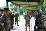 A member of the Corpo de Fuzileiros Navais (right) reports to U.S. Marine Col. Omar J. Randal.