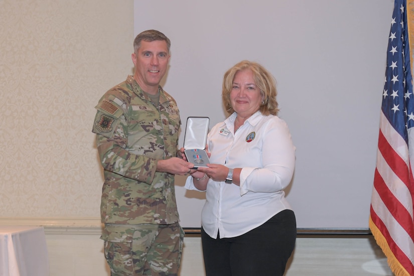 U.S. Air Force Maj. Gen. John Klein, U.S. Air Force Expeditionary Center commander, presents Cheryl Clark, Palmetto Military Support Group president, with the Commander’s Public Service Award medal during the Honorary Commander Induction Ceremony at Joint Base Charleston, Nov. 2, 2023.