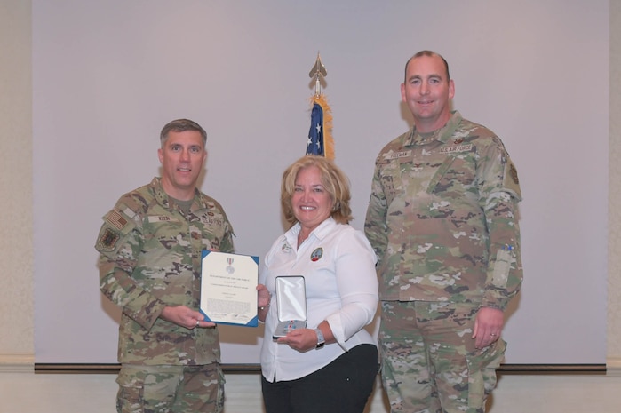 U.S. Air Force Maj. Gen. John Klein, U.S. Air Force Expeditionary Center commander and Col. Michael Freeman, 628th Air Base Wing and Joint Base Charleston commander, presents Cheryl Clark, Palmetto Military Support Group president, with the Commander’s Public Service Award medal during the Honorary Commander Induction Ceremony at Joint Base Charleston, Nov. 2, 2023.