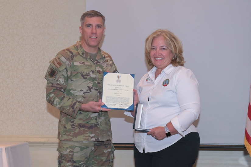 U.S. Air Force Maj. Gen. John Klein, U.S. Air Force Expeditionary Center commander, presents Cheryl Clark, Palmetto Military Support Group president, with the Commander’s Public Service Award during the Honorary Commander Induction Ceremony at Joint Base Charleston, Nov. 2, 2023.