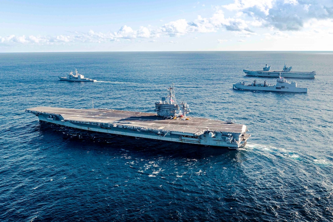 Four ships sail in formation through a body of water.