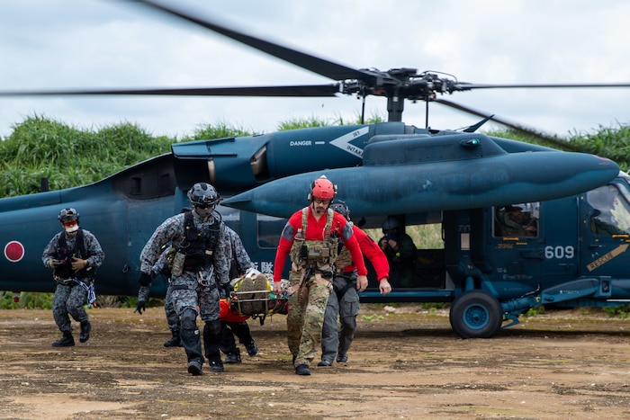 Japan Air Self-Defense Force and U.S. Air Force pararescuemen carry a simulated search and rescue victim to safety during an exercise, Jan. 19, 2023, at Ukibaru Island. The annual bilateral training exercise strengthens trust and interoperability capabilities between JASDF and U.S. Air Force rescue teams. (U.S. Air Force photo by 1st Lt. Robert Dabbs)