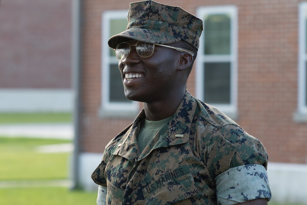 A Marine smiles while standing outside a building