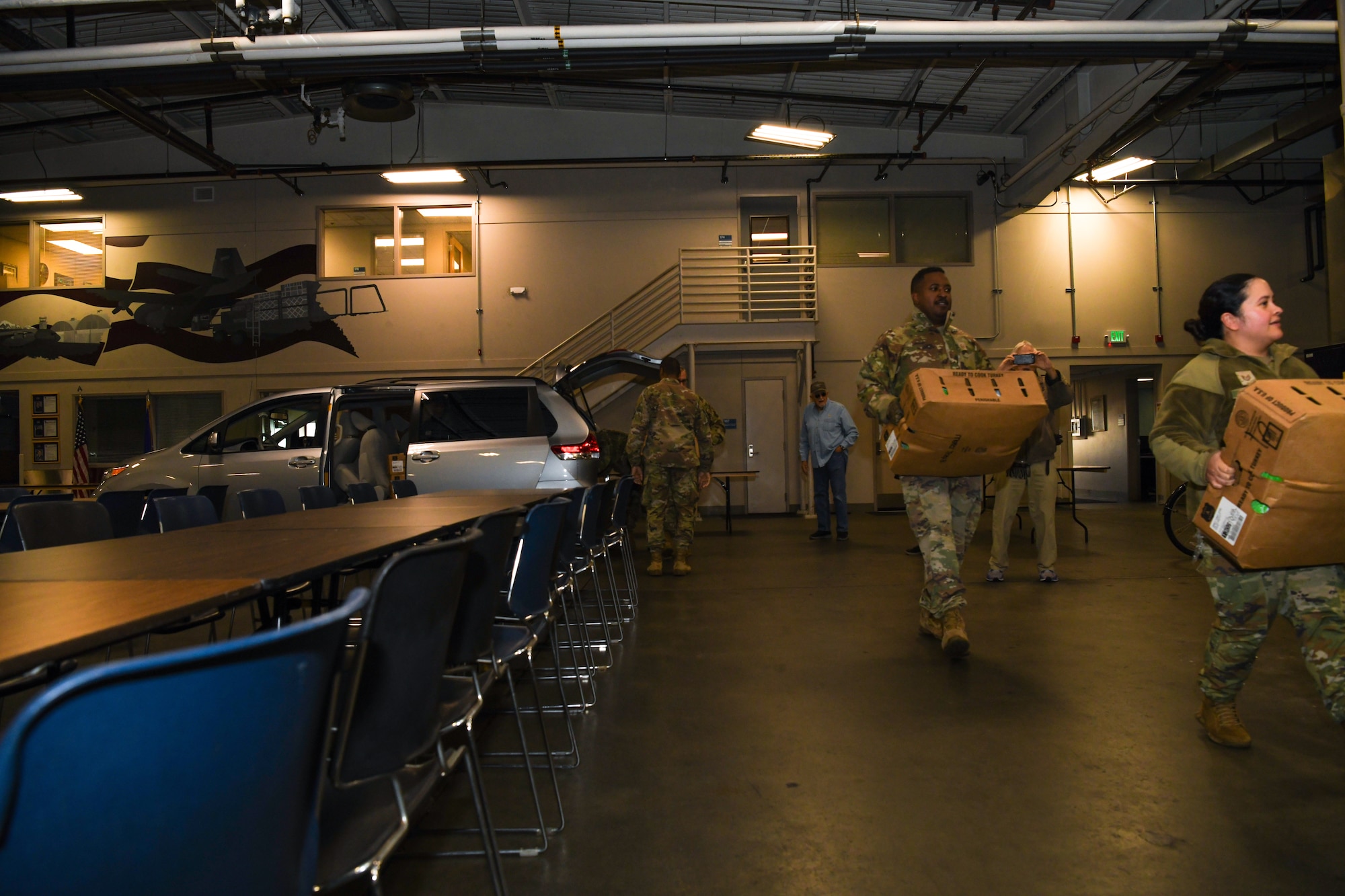 Airmen carry boxes of frozen turkeys in a warehouse during a community relations event.