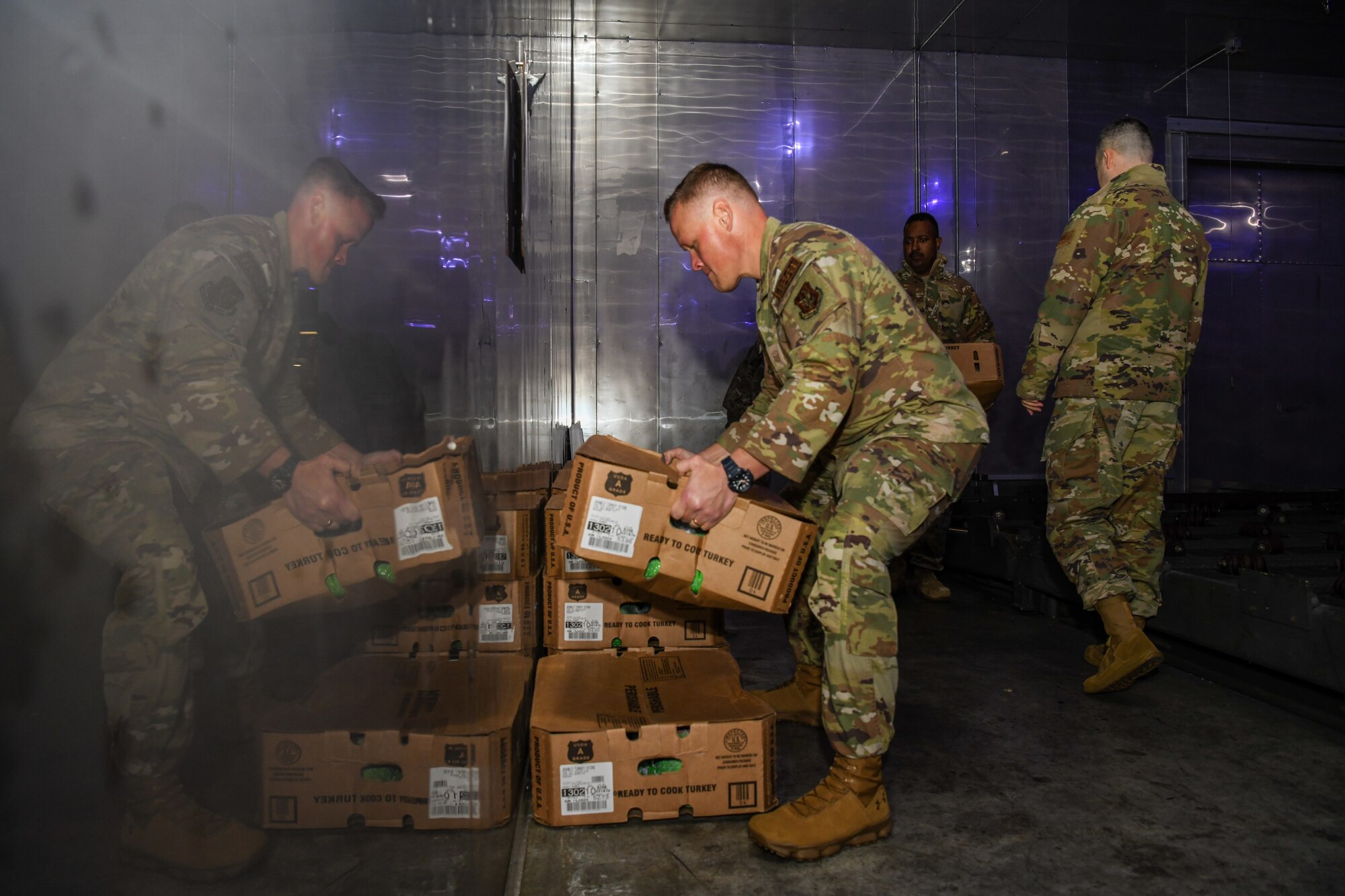 Airmen move boxes of frozen turkeys inside a cooler during a community relations event.
