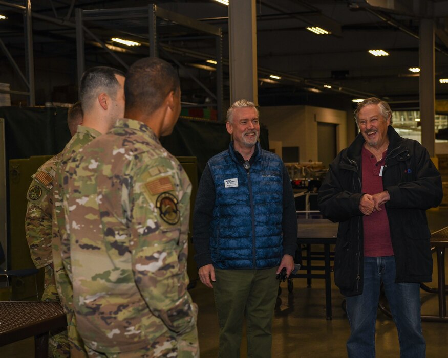 Two Airmen in speak with two civilians during a community relations event.