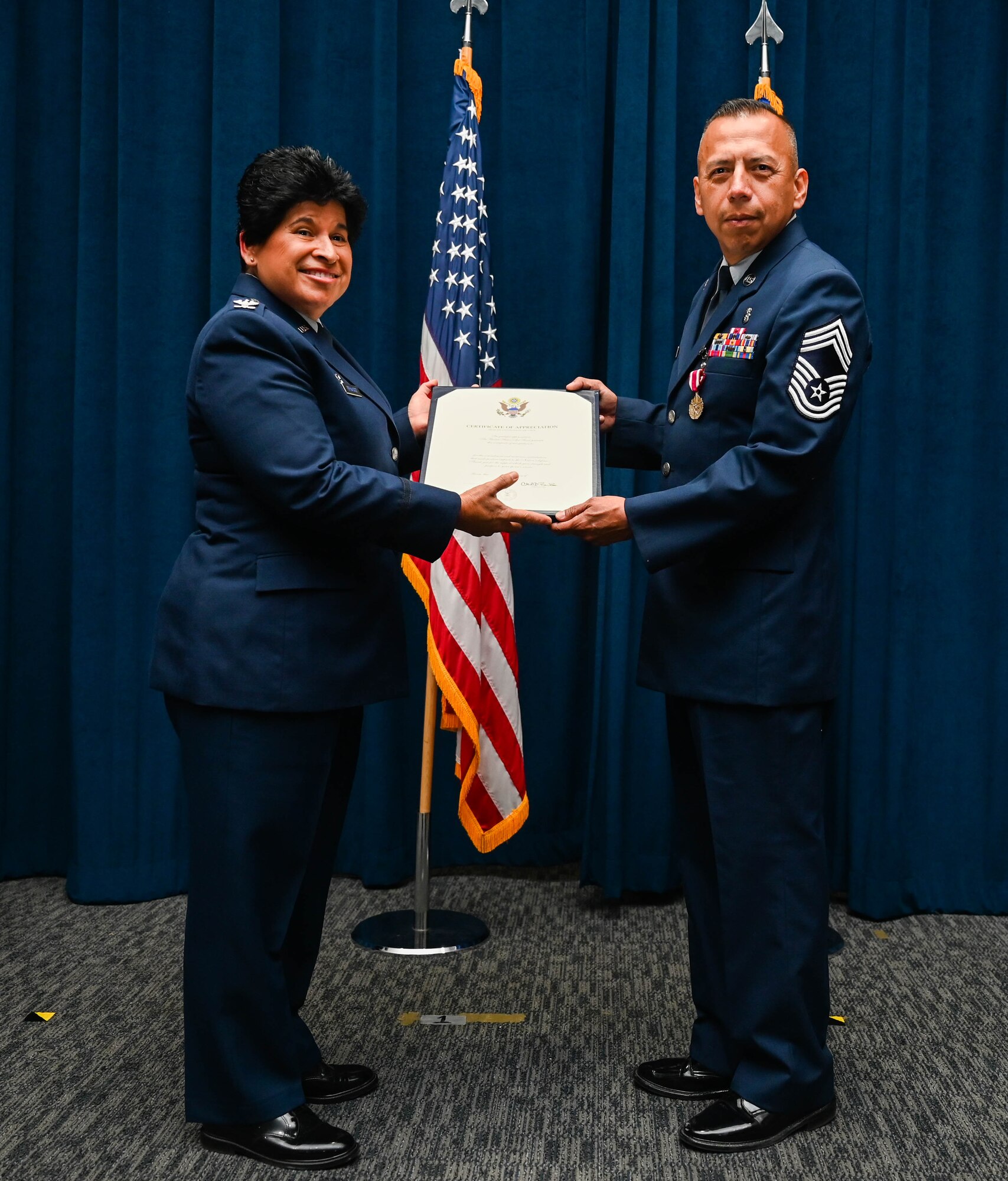 Col. Sylvia Fernandez, 433rd Aeromedical Evacuation Squadron commander, presents a certificate of retirement to Chief Master Sgt. Ernesto Flores, 433rd Medical Group superintendent, during a ceremony on Joint Base San Antonio-Lackland, Texas, October 14, 2023.
