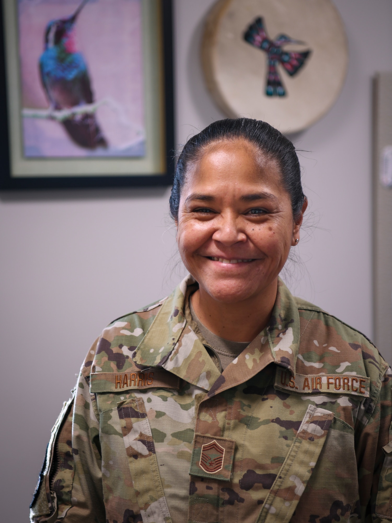 A female airman stand in front of items representing her Native American heritage.