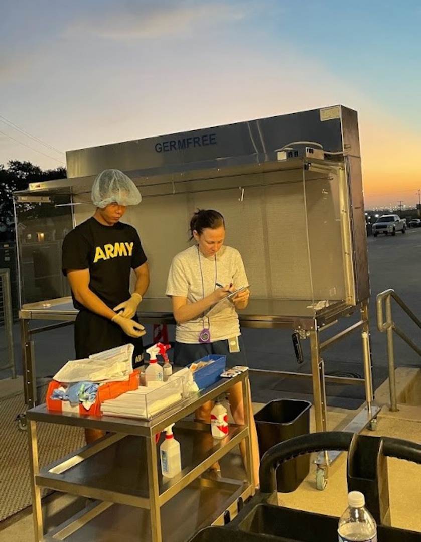 Master Sgt. Lacey Harris (right), Air Force Senior Enlisted Lead, grades a pharmacy technician student’s compounding product prepared on outpatient pharmacy hoods located on the loading dock of Heritage Hall.