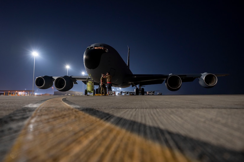 A military jet is parked on a tarmac at night.