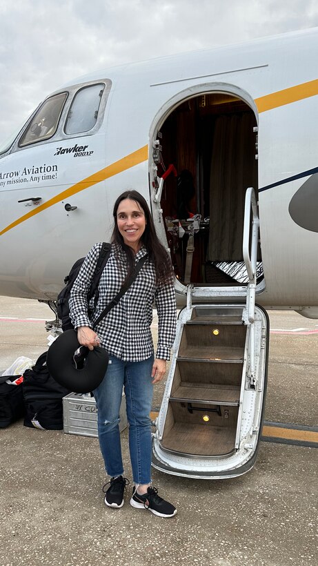 Woman stands outside by the stairs of a small plane