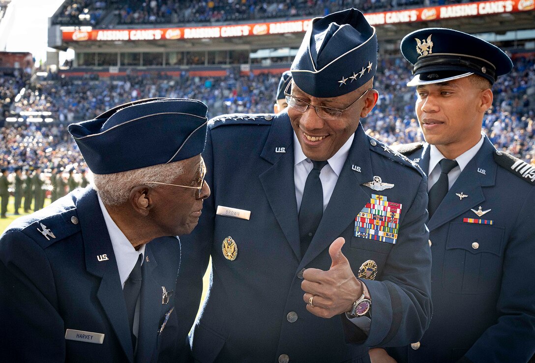 Air Force Gen. CQ Brown, Jr. smiles and gives a thumbs-up to a veteran in uniform at a stadium.