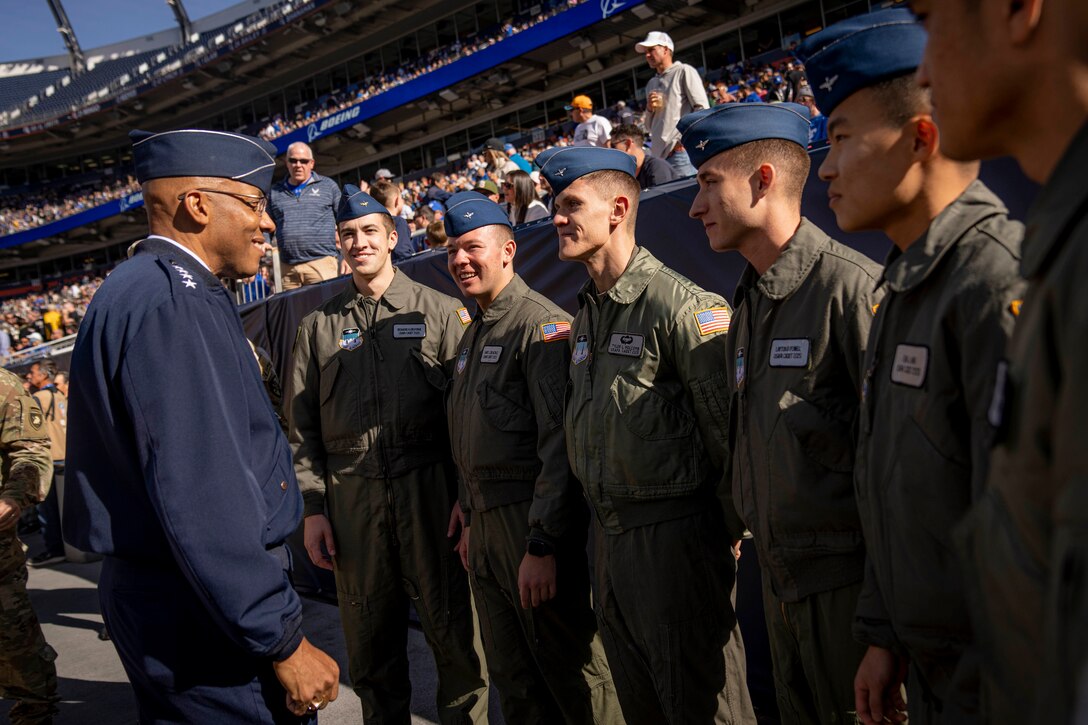 Air Force Gen. CQ Brown, Jr. talks with a group of Air Force cadets on the sidelines of a packed stadium.